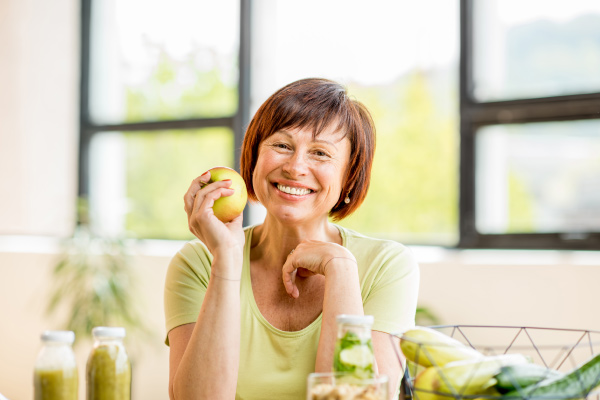 senior woman eating apple with permanent dental implants